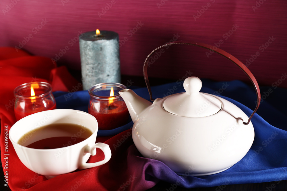 Composition with tea in cup and teapot and candles
