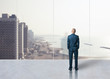 Businessman standing in the room and looking at city