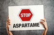 Hands holding banner with STOP ASPARTAME message