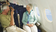 Deutschland,München,Bayern,älterer Mann,der Foto aus Handy in der Economy-Klasse -Verkehrsflugzeug