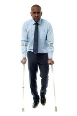 Middle aged man walking with two crutches