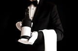 Fototapeta Londyn - Waiter in tuxedo holding a bottle of red wine
