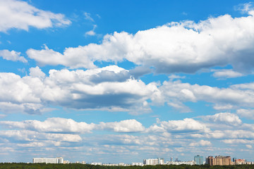 Wall Mural - cityscape with white fluffy clouds in blue sky