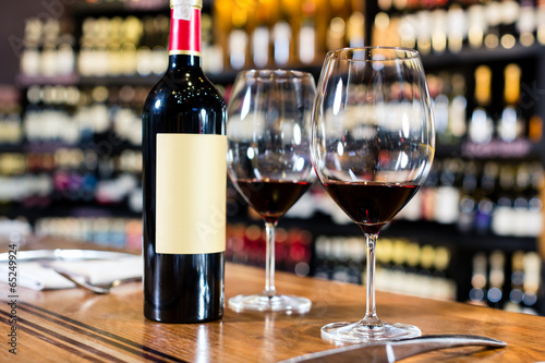 Fotografía Bottle of red wine and two glasses in wine shop