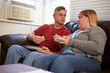 © Monkey Business - Couple With Poor Diet Sitting On Sofa Eating Meal