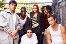 Gang Of Young People In Urban Setting Standing By Fence