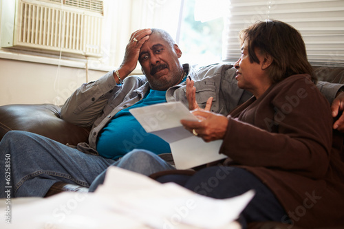 Fotografía Worried Senior Couple Sitting On Sofa Looking At Bills