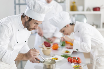 Wall Mural -  chef preparing a dish his team in the background