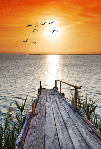 Fototapeta na wymiar embarcadero de madera en el mar mirando el amanecer