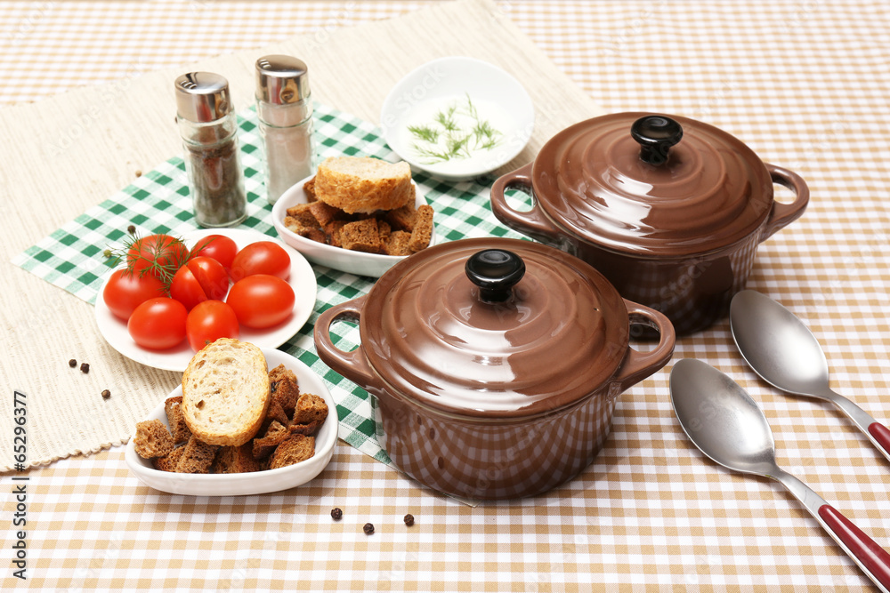 Tasty soup in saucepans on tablecloth, close up