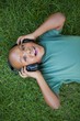 © WavebreakmediaMicro - Little boy lying on grass listening to music smiling at camera