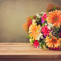 Wall Mural - Flower bouquet on wooden table over grunge background