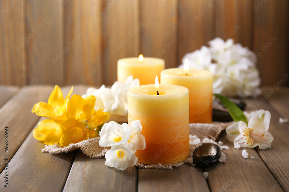 Beautiful candles with flowers on wooden background