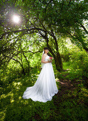  bride in long dress under big trees at old forest