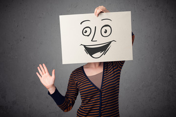 Wall Mural - Woman holding a cardboard with smiley face on it in front of her