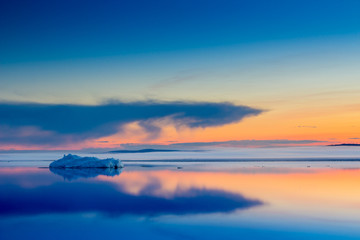 The melting iceberg on spring mountain lake in the setting sun.