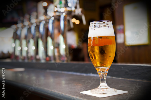 Naklejka na szybę Glass of light beer on a dark pub