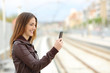 © Antonioguillem - Woman browsing social media in a train station