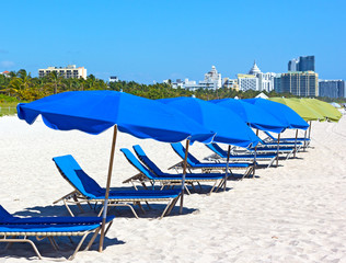 Lounge chairs under colorful beach umbrellas and city skyline