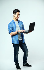 Sticker - cheerful asian man using laptop on gray background