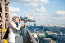Young Blonde Woman Looks Through Telescope On Top Of The Eiffel