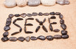 mot sexe écrit avec des galets sur le sable 