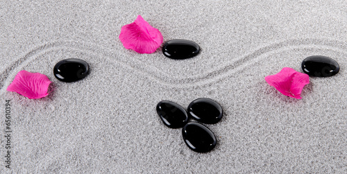 Naklejka na szybę Composition of black pebbles with flower petals on the sand