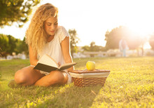Pretty Blond Young Woman Reading A Book At Park