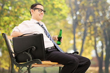 Canvas Print - Businessman taking a break in park with a beer