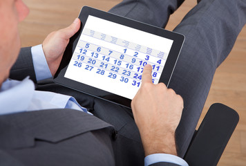 Poster - Businessman Using Calendar On Digital Tablet In Office