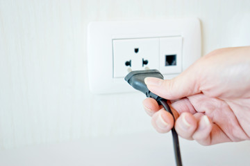 Electric cable with hand and Electrical Outlet on the Wall.