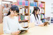 © taka - young asian women reading a book in the library