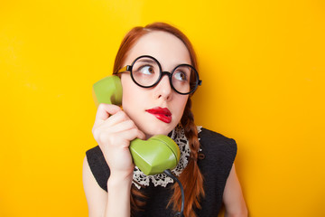 Wall Mural - Redhead girl with green phone on yellow background.