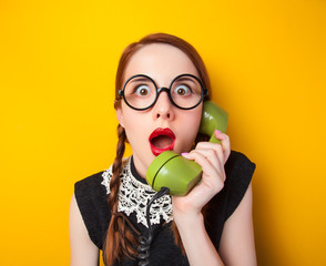 Wall Mural - Redhead girl with green phone on yellow background.