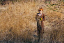 Young Woman Walking In Golden Dried Grass Field