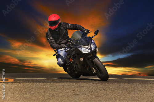 Naklejka na szybę young man riding big bike motorcycle on asphalt roads against be