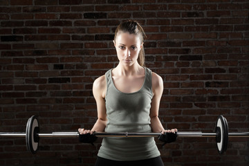 Sexy fit woman lifting dumbbells on brick background