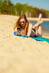 Canvas Print - Summer vacation Girl with phone tanning on beach