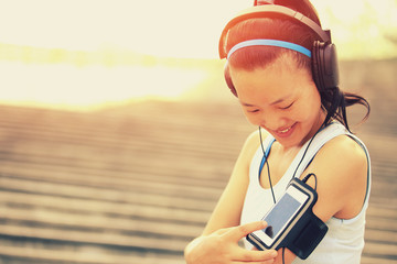 Wall Mural - woman unner listening to music in headphones from smart phone