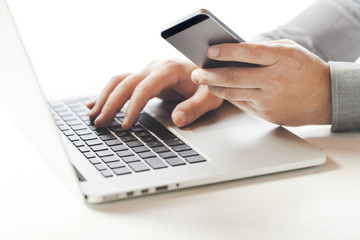 Close up business man using  a laptop and mobile phone