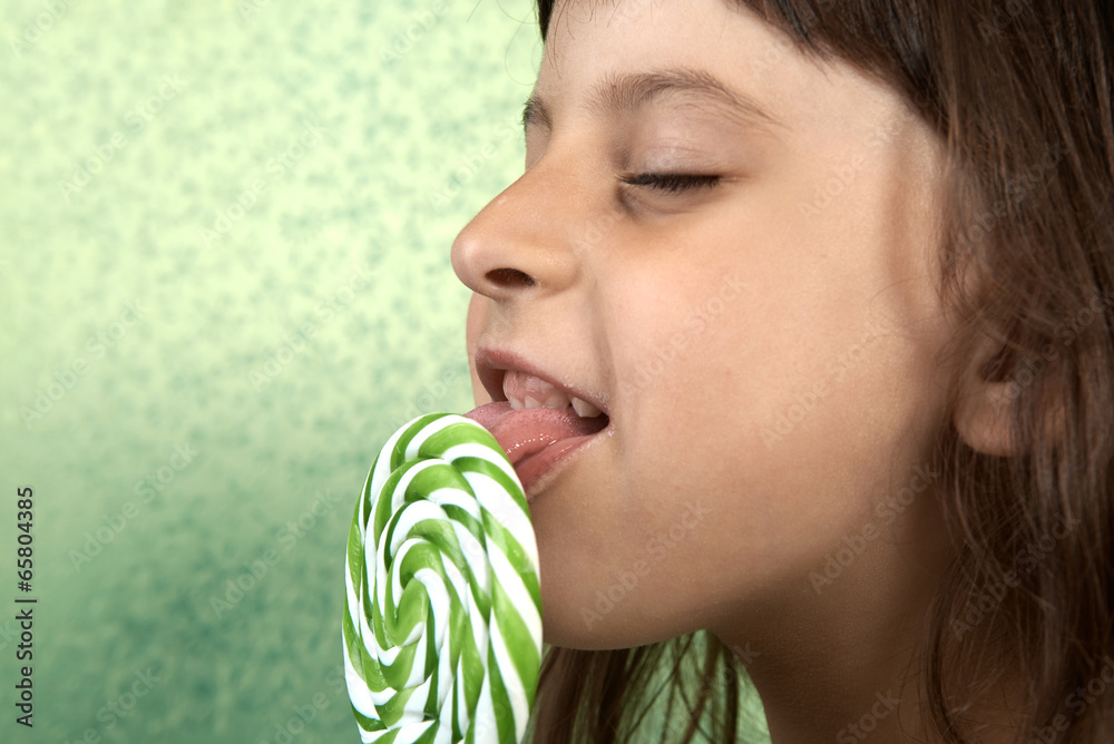 girl enjoy licking a lollipop. Stock Photo | Adobe Stock