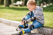 © Soloviova Liudmyla - Little boy lace his roller skate sitting on the sidewalk