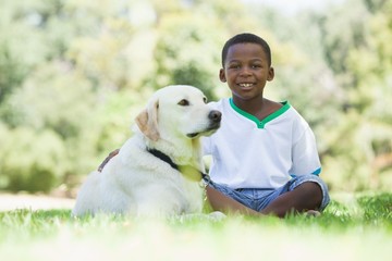 Wall Mural - Little boy sitting with his pet labrador in the park