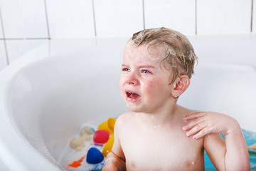 Cute little toddler boy of two years having fun by taking bath i