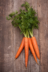 Wall Mural - fresh carrot bunch on grungy wooden background