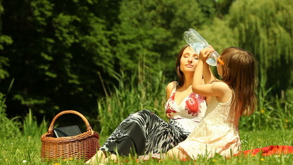 Wall Mural - Picnic. Mother with daughter relaxing. Child drinking water.