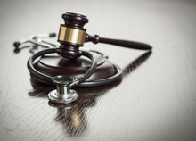 Gavel And Stethoscope On Reflective Table