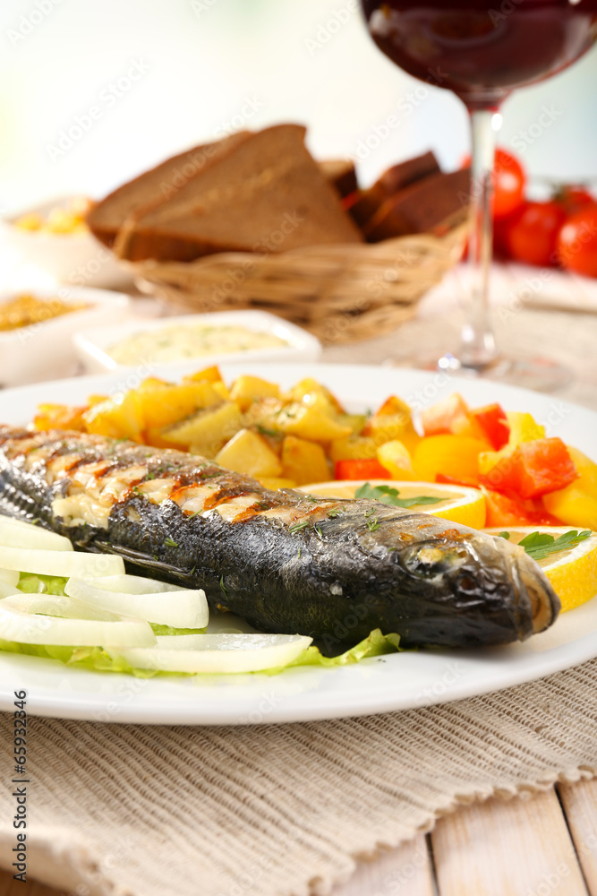 Delicious grilled fish on plate on table close-up