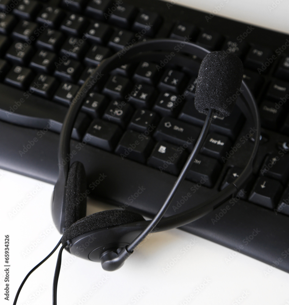 Headphone and keyboard close-up on white desk background