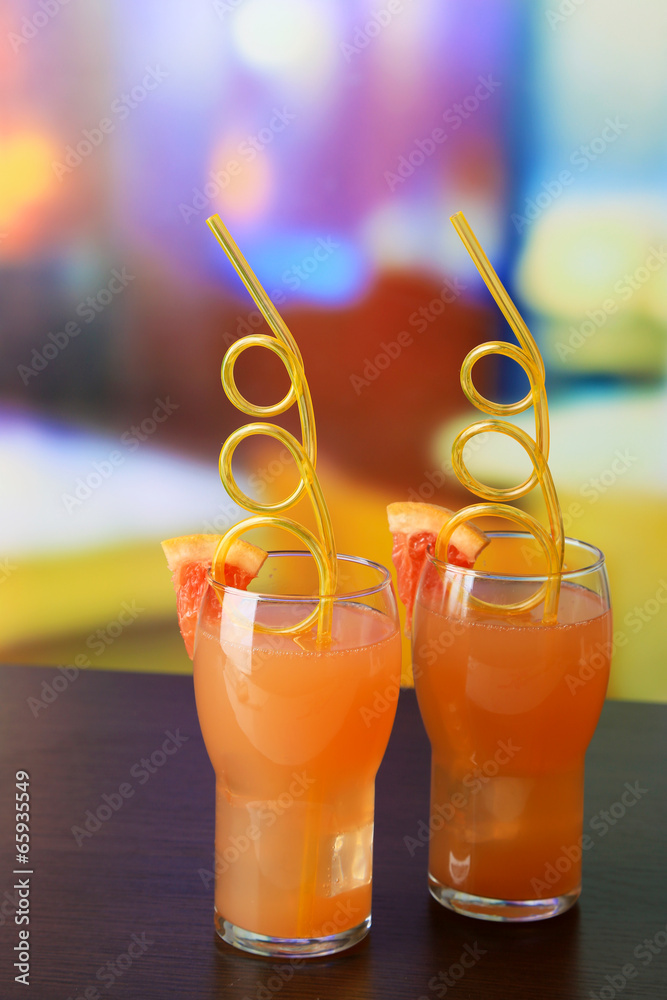 Grapefruit cocktail with cocktail straw on bright background